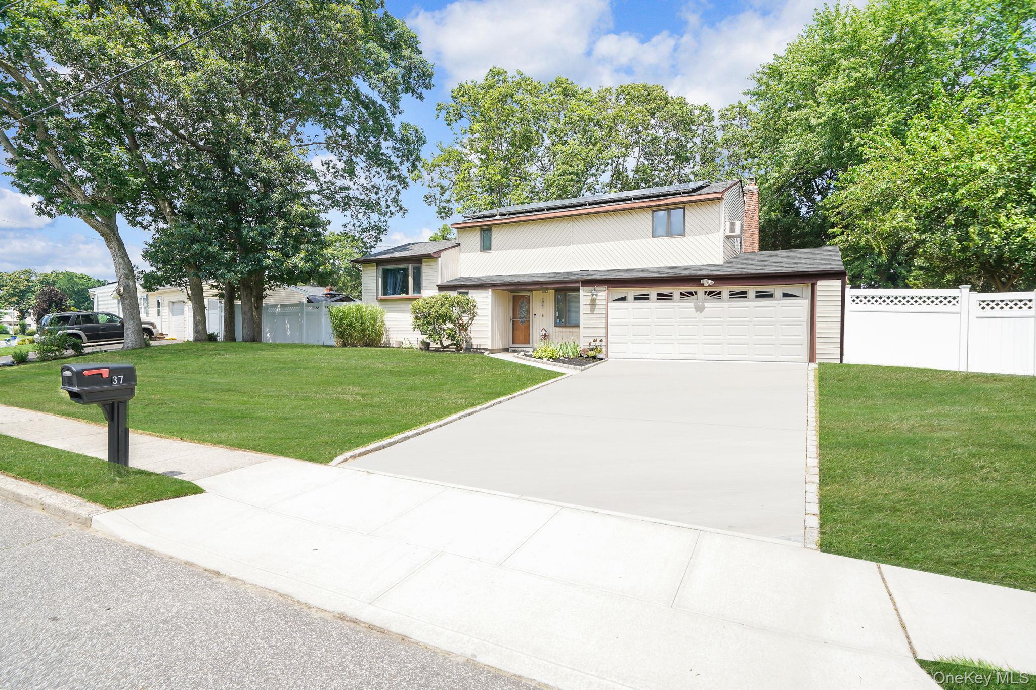 Split level home featuring roof mounted solar panels, concrete driveway, and a chimney