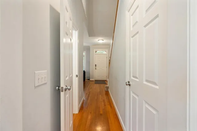 a view of a hallway with wooden floor and a bathroom