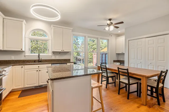 a kitchen with granite countertop a table chairs stove and white cabinets