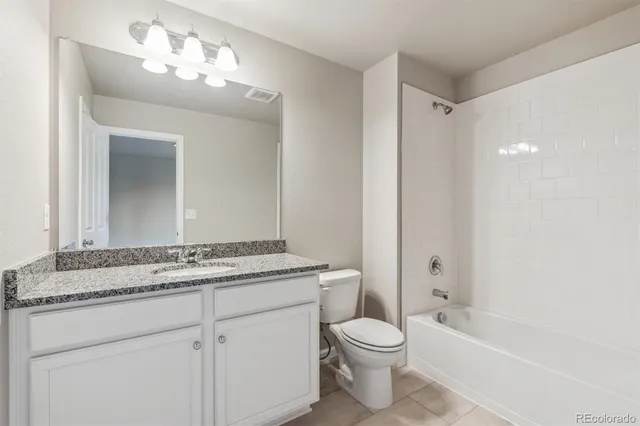 a bathroom with a granite countertop sink a toilet mirror and bathtub
