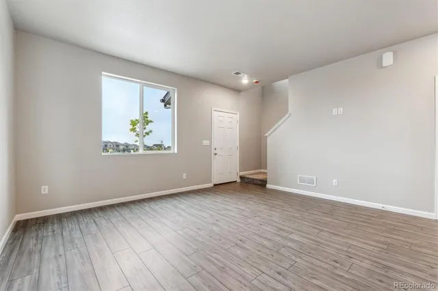a view of an empty room with wooden floor and painting on the wall