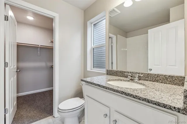 a bathroom with a granite countertop sink a toilet and a mirror