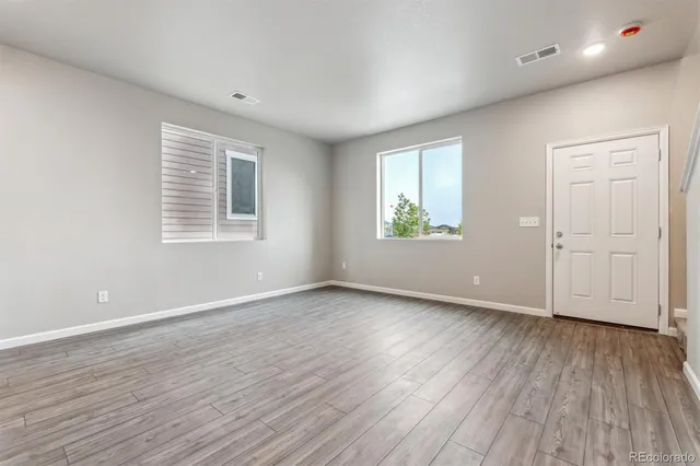 an empty room with wooden floor and windows