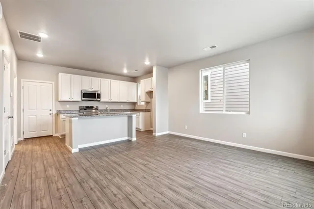 a view of kitchen with granite countertop stainless steel appliances sink and cabinets