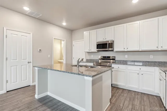 a kitchen with granite countertop white cabinets and black stainless steel appliances