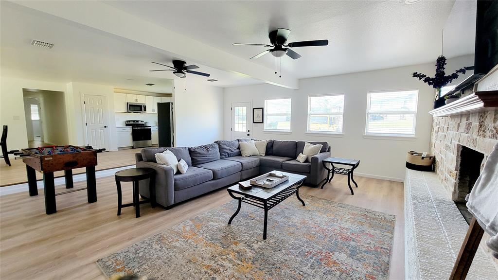 1447 West Lingleville Road Stephenville, TX 76401 - Photo 4 of 12 Living area featuring plenty of natural light, light wood-style floors, a ceiling fan, and a stone fireplace