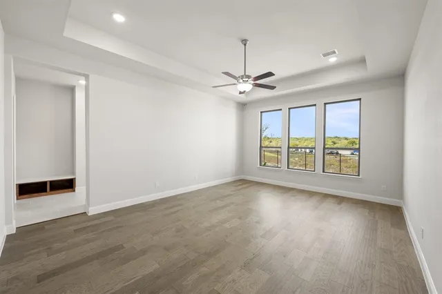 an empty room with wooden floor chandelier and windows