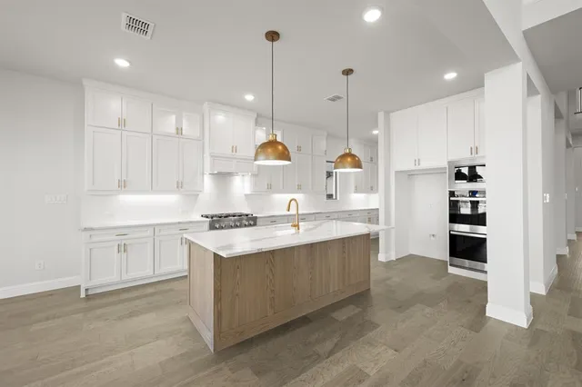 a kitchen with kitchen island a sink stainless steel appliances and cabinets