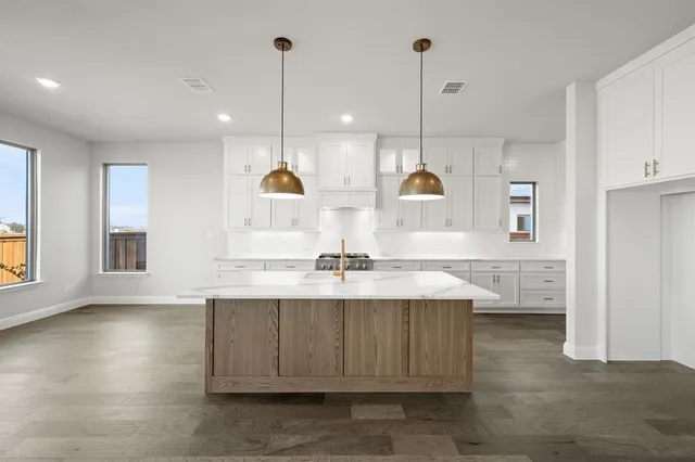 a large kitchen with kitchen island a stove a sink a center island and wooden floor