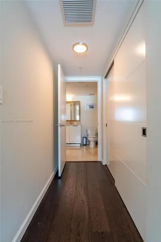 a view of a room with wooden floor a kitchen space and a window