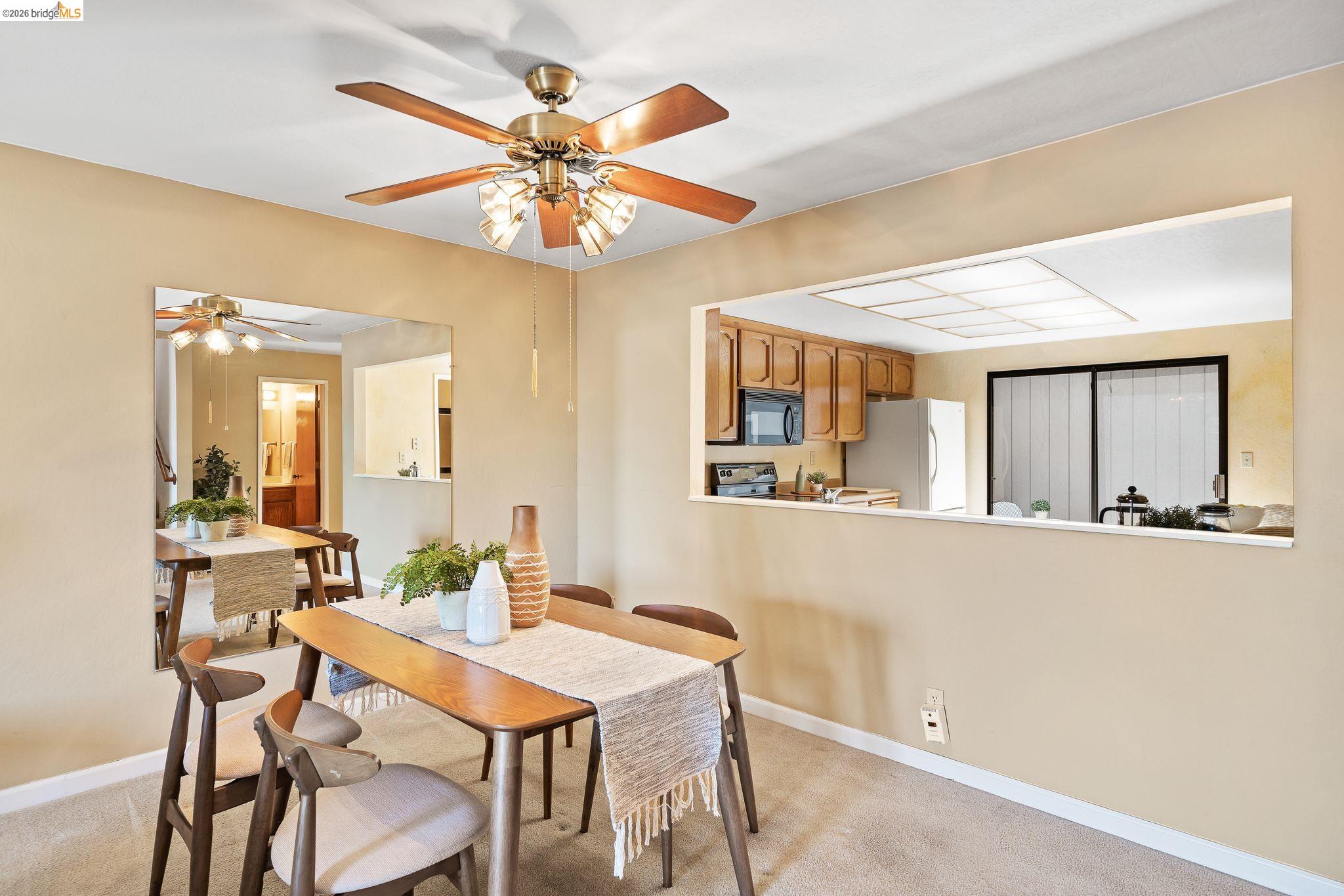 2051 Sand Point Road Discovery Bay, CA 94505 - Photo 15 of 47 Dining area featuring a pass-through window to the kitchen, a ceiling fan with integrated lighting, and carpet flooring