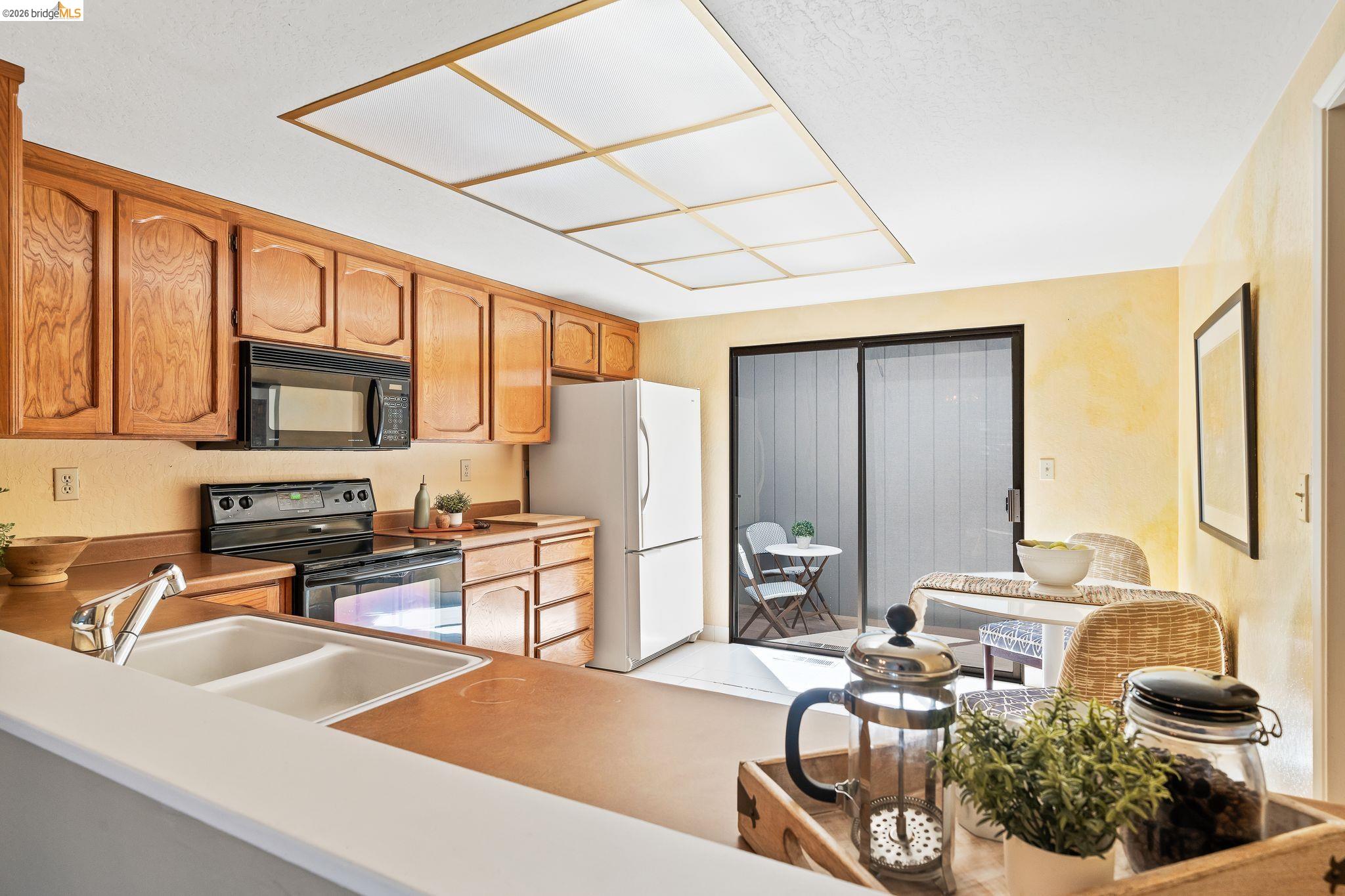 2051 Sand Point Road Discovery Bay, CA 94505 - Photo 17 of 47 Kitchen featuring wood cabinetry, a dual basin sink, and black appliances including an oven with stovetop and a built-in microwave