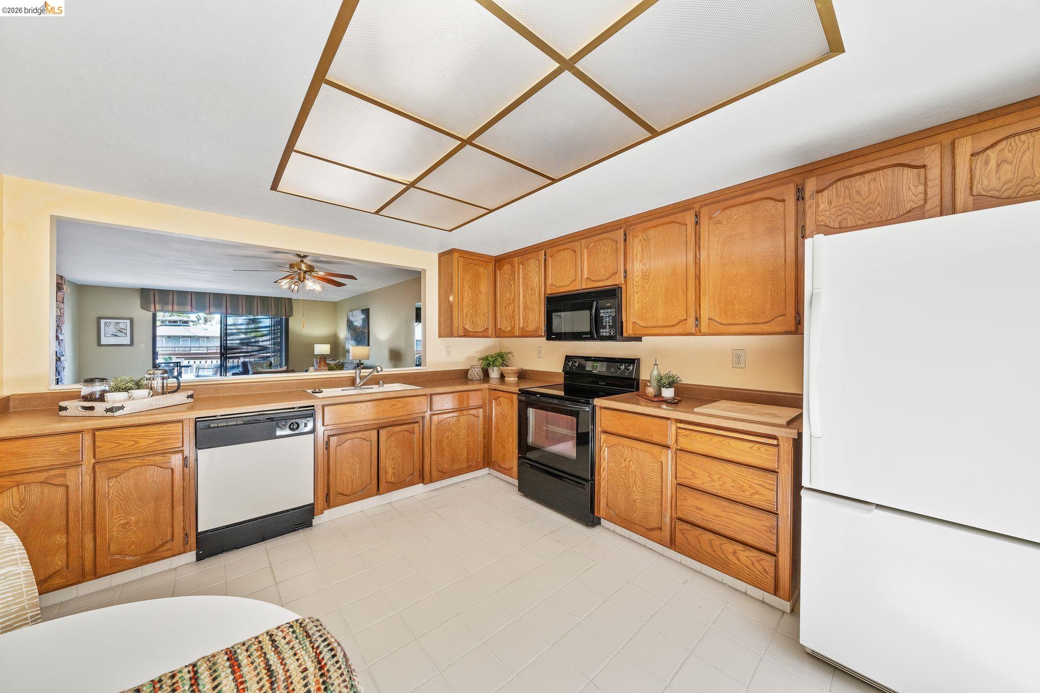 2051 Sand Point Road Discovery Bay, CA 94505 - Photo 19 of 47 U-shaped kitchen featuring wood cabinetry, tile flooring, and a pass-through window