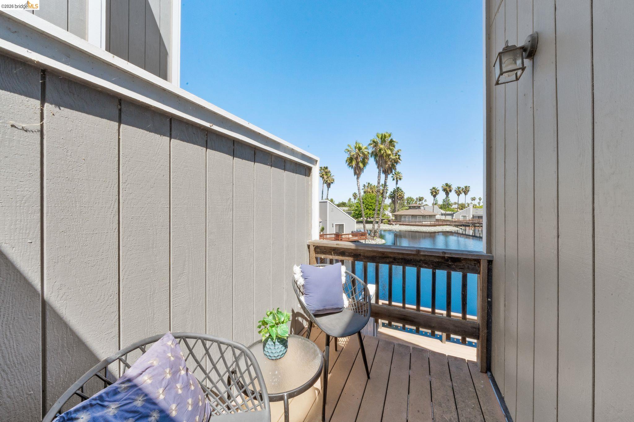 2051 Sand Point Road Discovery Bay, CA 94505 - Photo 27 of 47 Private balcony featuring wood-finish decking, a robust wood railing, exterior lighting, and water frontage with palm tree landscaping