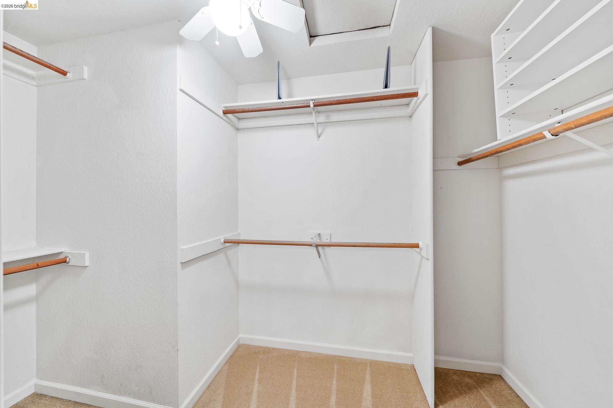 2051 Sand Point Road Discovery Bay, CA 94505 - Photo 30 of 47 Walk-in closet featuring built-in shelving, multiple hanging rods, a ceiling fan, and carpet flooring