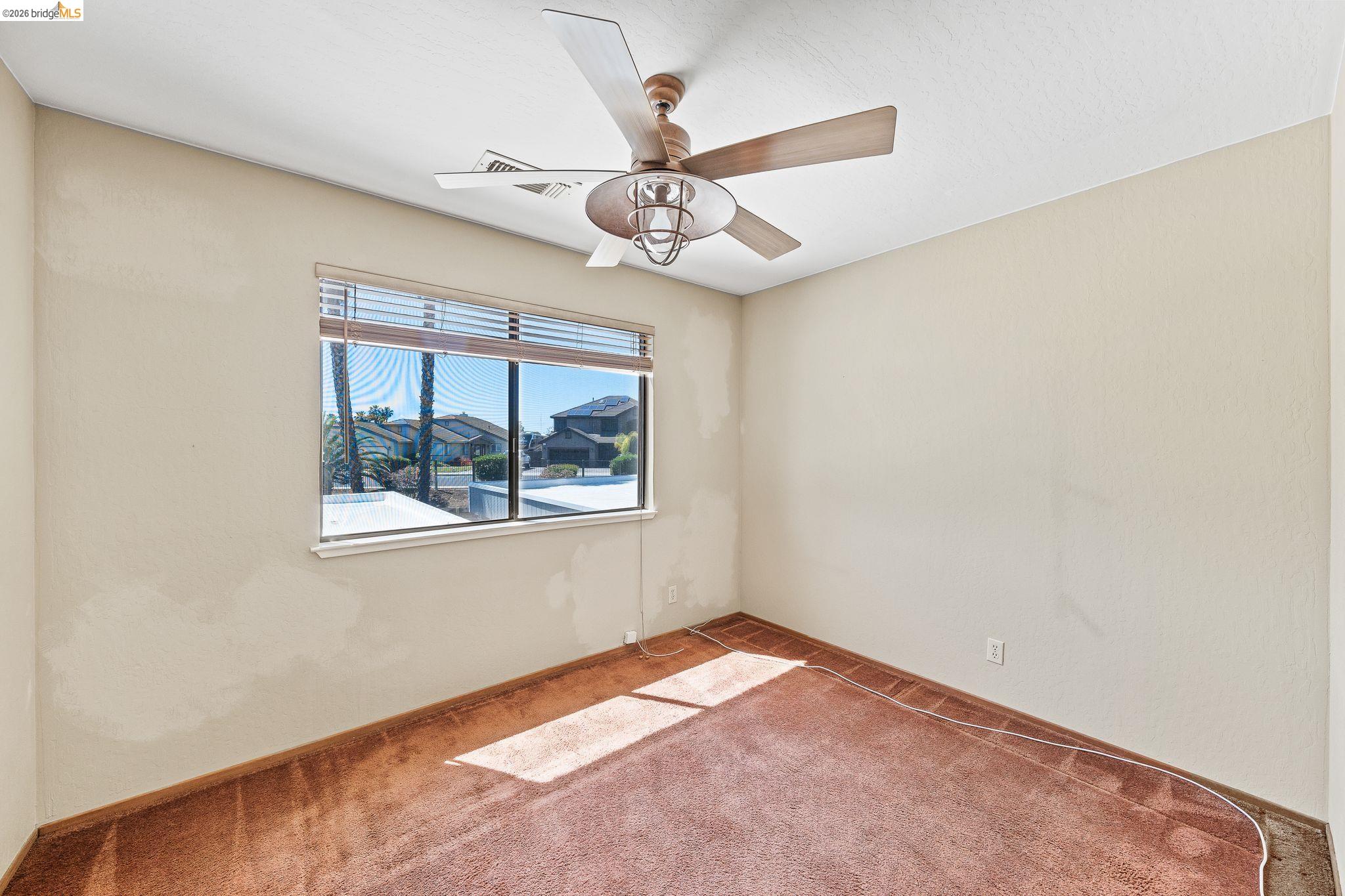 2051 Sand Point Road Discovery Bay, CA 94505 - Photo 35 of 47 Light-filled room featuring a ceiling fan with integrated lighting, a broad window with horizontal blinds, and a carpeted floor