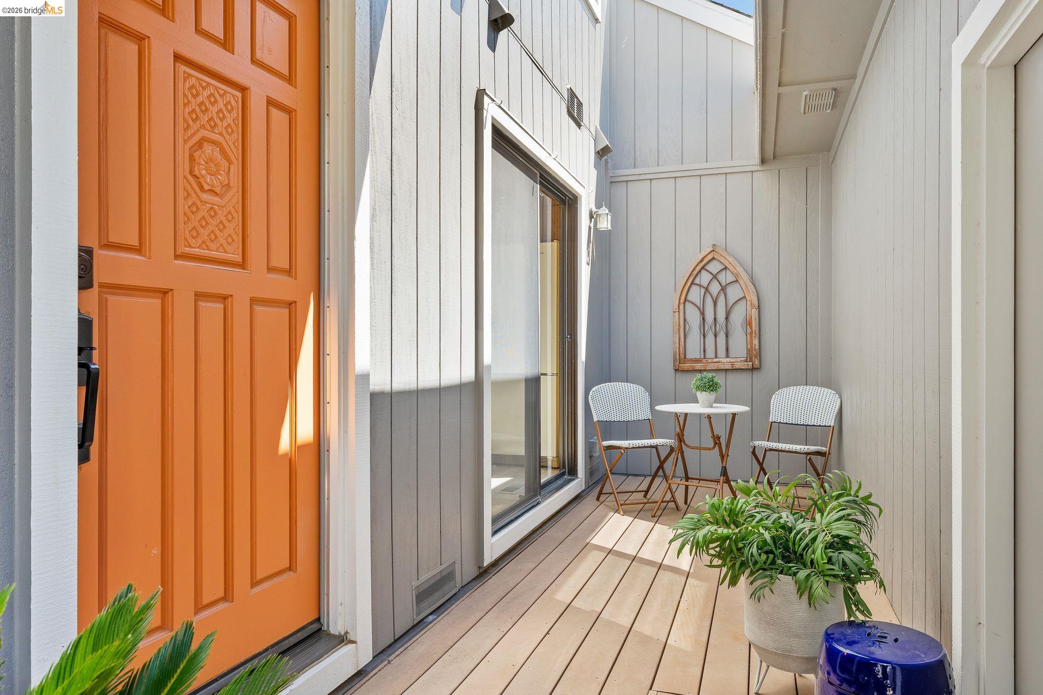 2051 Sand Point Road Discovery Bay, CA 94505 - Photo 7 of 47 Inviting exterior entrance featuring a vibrant orange paneled door with decorative detailing, vertical siding, and a private outdoor deck area