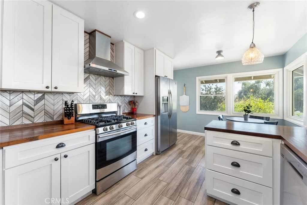 4380 Miramonte Place Riverside, CA 92501 - Photo 20 of 73 a kitchen with stainless steel appliances a stove a sink dishwasher a refrigerator and white cabinets with wooden floor