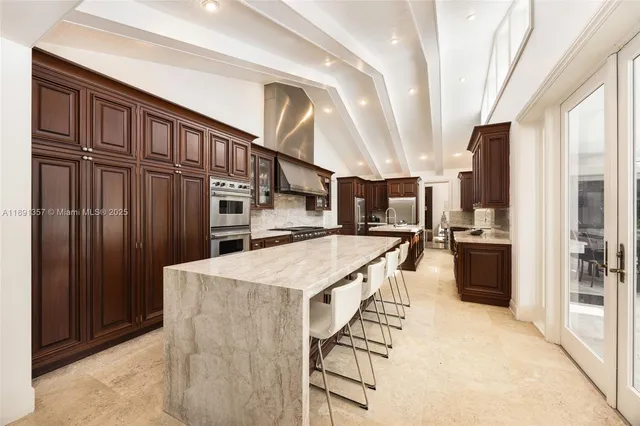 a kitchen with stainless steel appliances kitchen island granite countertop a refrigerator oven a sink dishwasher and white cabinets with wooden floor