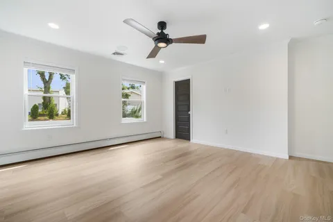 a view of an empty room with a window and wooden floor