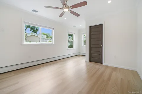 an empty room with wooden floor ceiling fan and windows