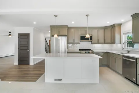 a kitchen with kitchen island a counter top space a sink stainless steel appliances and cabinets
