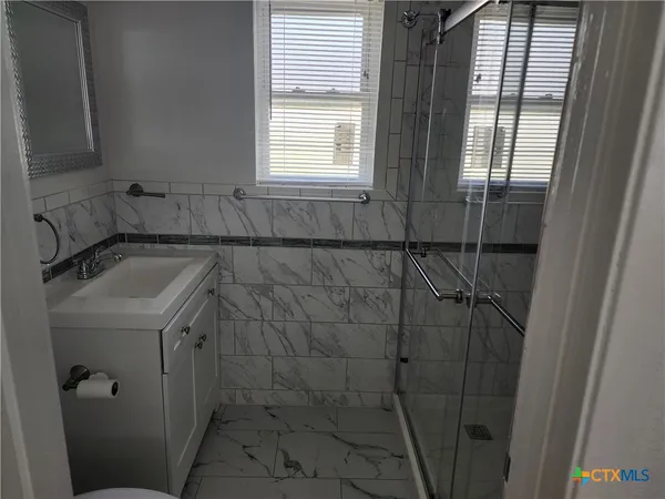 a bathroom with a sink a window and shower