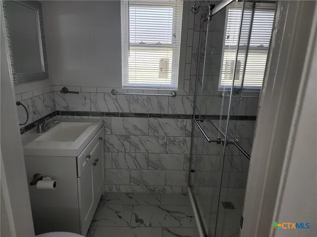 a bathroom with a sink a window and shower