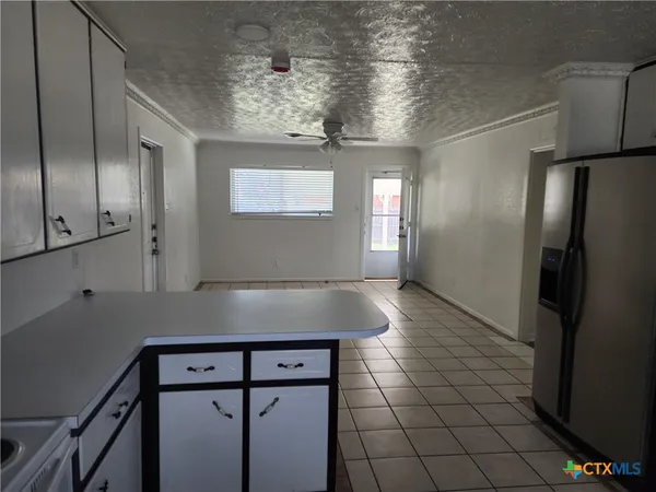 a view of a refrigerator in kitchen and an empty room