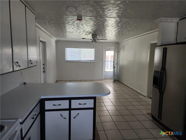 a view of a refrigerator in kitchen and an empty room
