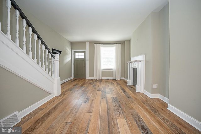 a view of an empty room with wooden floor and windows
