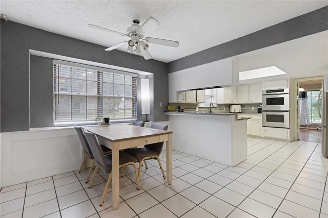 a kitchen with stainless steel appliances kitchen island granite countertop a sink a stove a dining table and chairs