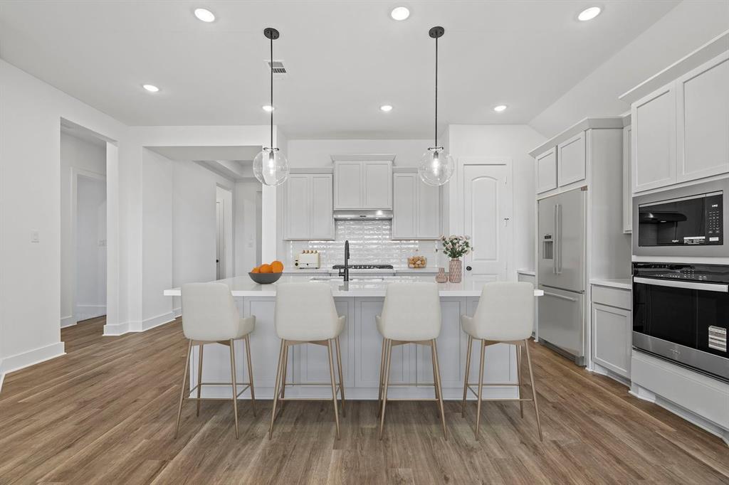 1792 Monarch Way Oak Point, TX 75068 - Photo 5 of 26 a large white kitchen with a sink chairs and refrigerator