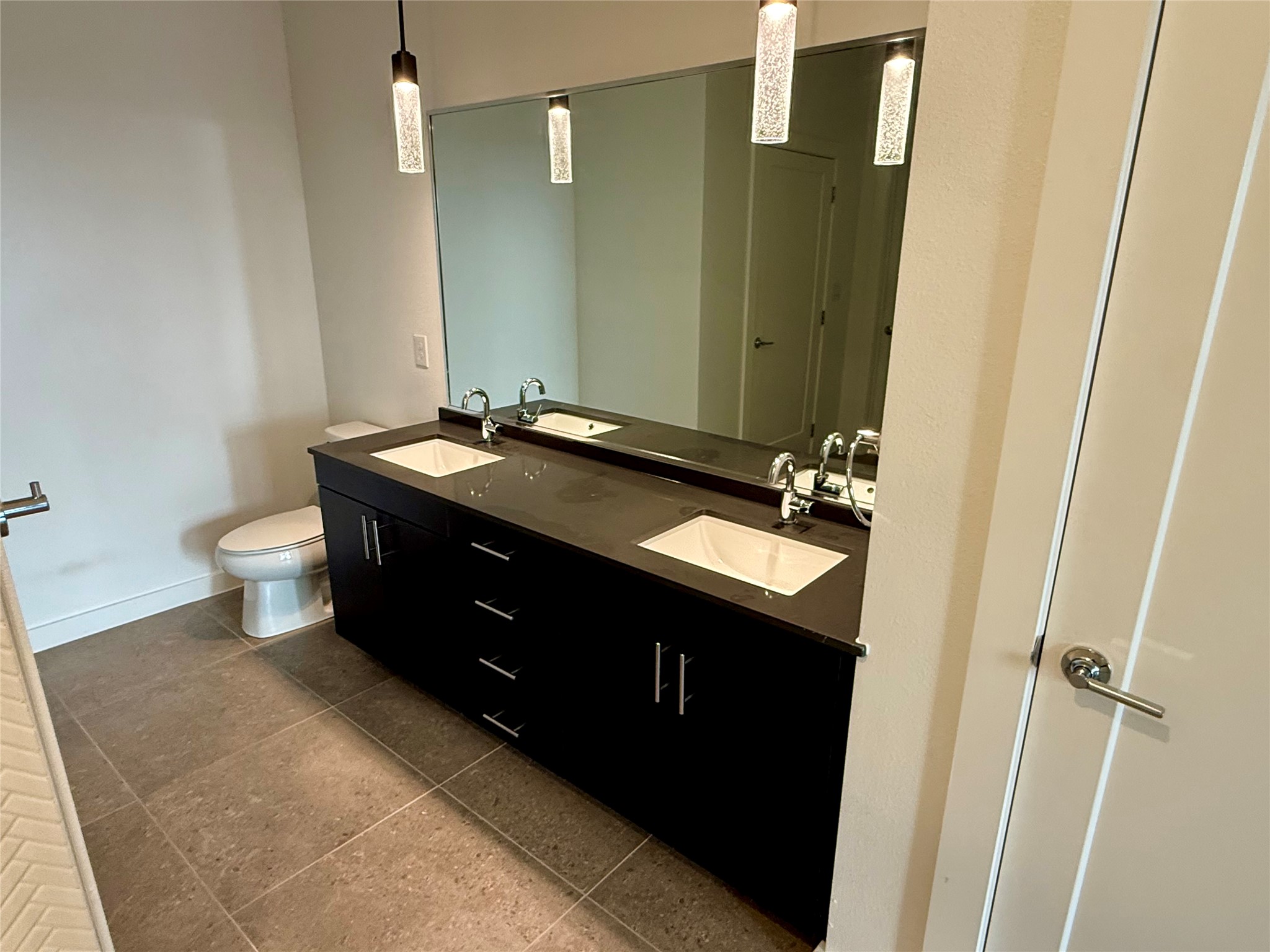 4801 Springdale Road, Unit 1106 Austin, TX 78723 - Photo 11 of 22 A spacious double vanity anchors this modern bathroom completed with large format floor tiles.