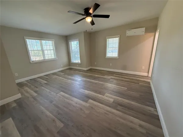 a view of empty room with wooden floor and fan