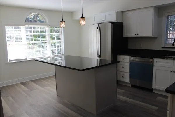 a kitchen with stainless steel appliances granite countertop a refrigerator a sink a stove and a wooden floors