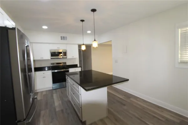 a kitchen with a refrigerator and white cabinets