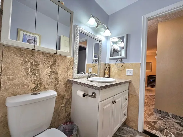 a bathroom with a granite countertop toilet sink and mirror