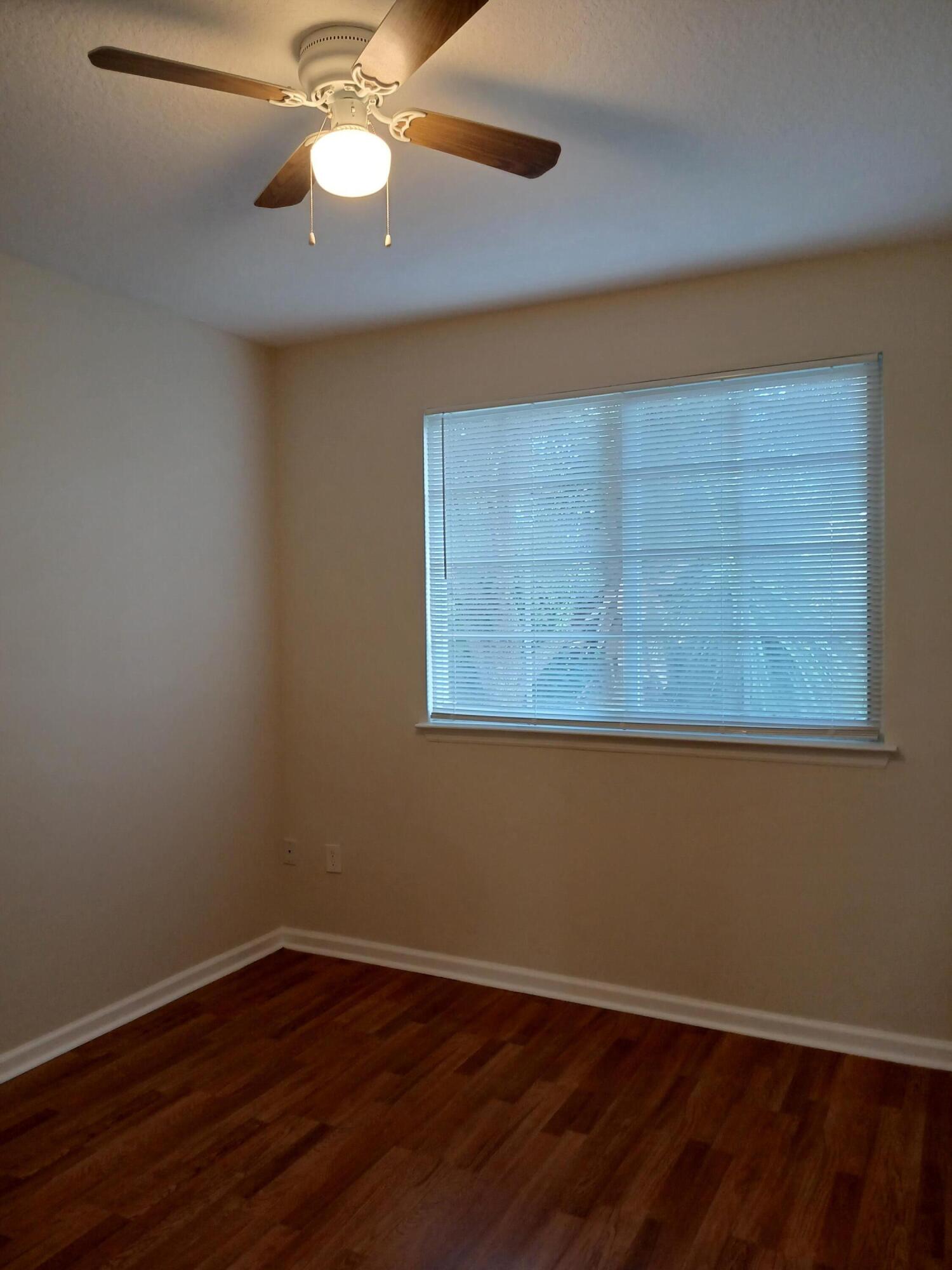 9857 Baywinds Boulevard, Unit 9212 Royal Palm Beach, FL 33411 - Photo 14 of 23 an empty room with wooden floor fan and windows