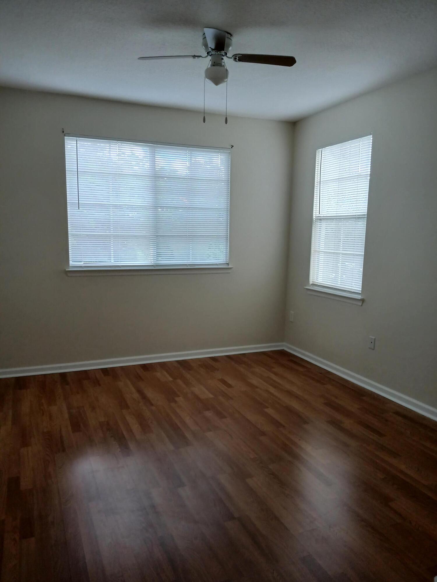 9857 Baywinds Boulevard, Unit 9212 Royal Palm Beach, FL 33411 - Photo 15 of 23 an empty room with wooden floor and windows