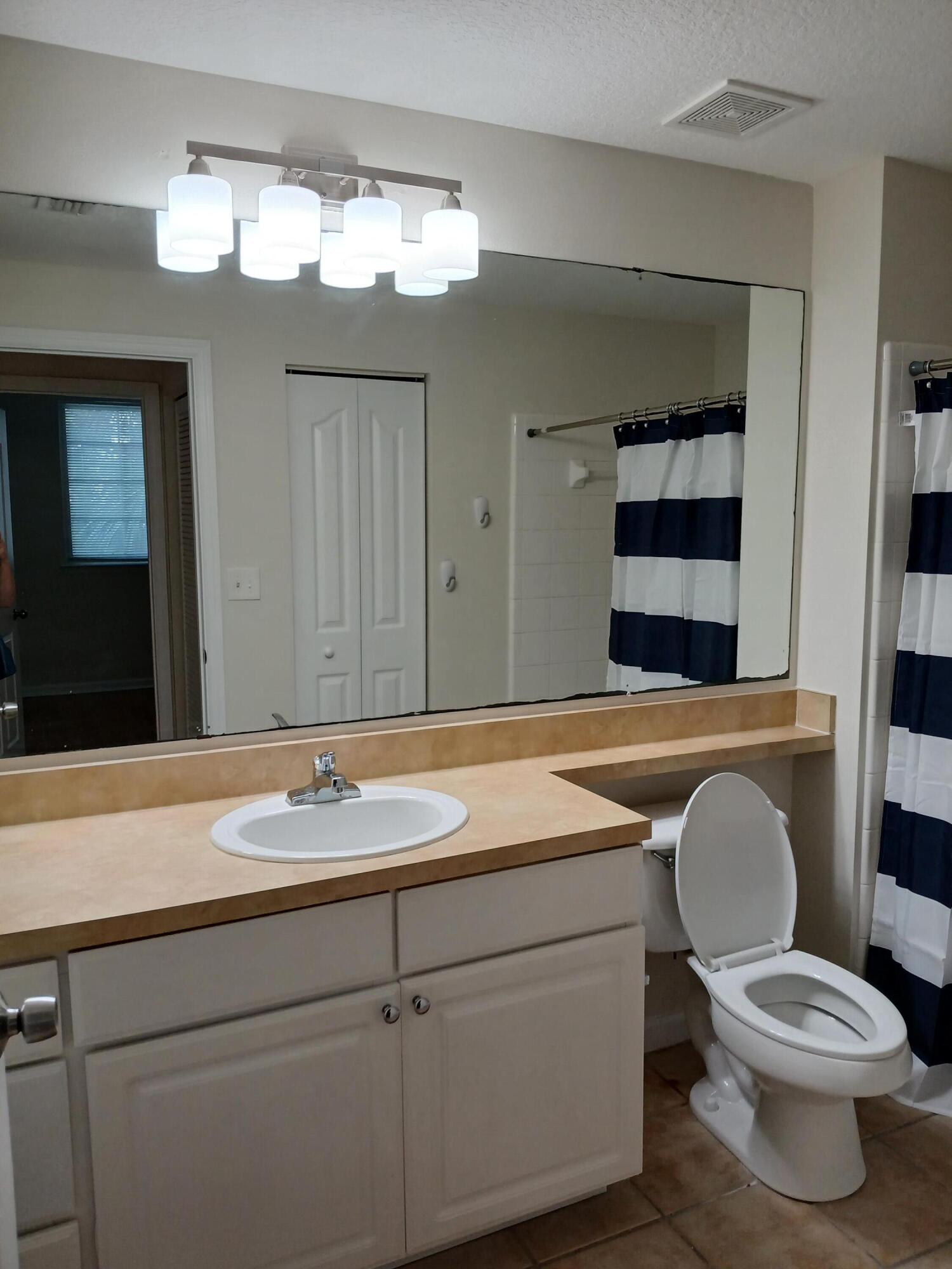 9857 Baywinds Boulevard, Unit 9212 Royal Palm Beach, FL 33411 - Photo 21 of 23 a bathroom with a toilet a sink and mirror