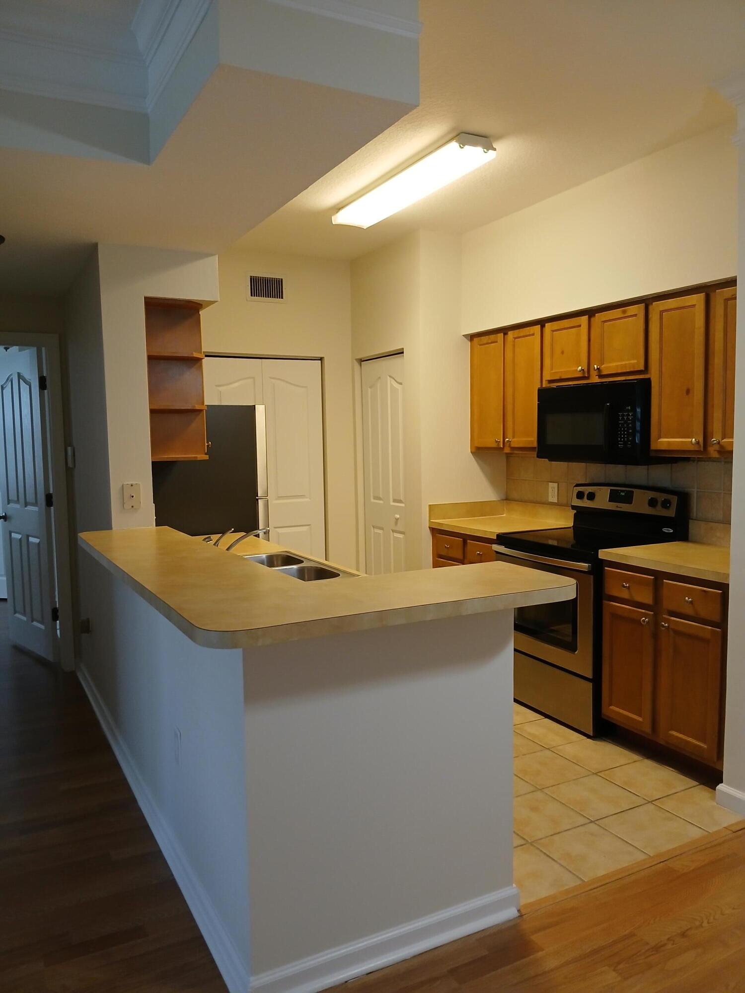 9857 Baywinds Boulevard, Unit 9212 Royal Palm Beach, FL 33411 - Photo 5 of 23 a kitchen with stainless steel appliances a stove and a refrigerator