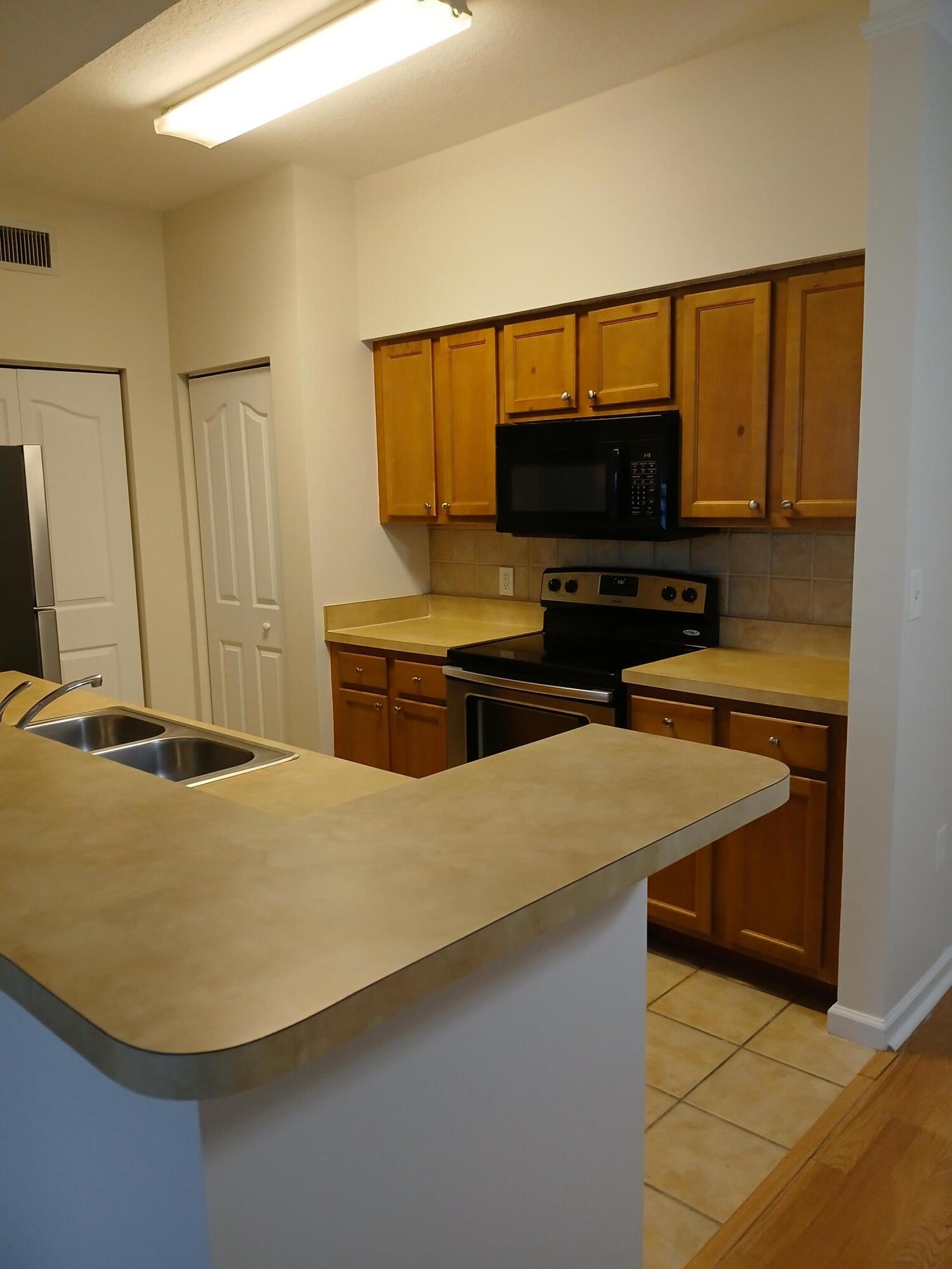 9857 Baywinds Boulevard, Unit 9212 Royal Palm Beach, FL 33411 - Photo 6 of 23 a bedroom with a bed and a flat screen tv