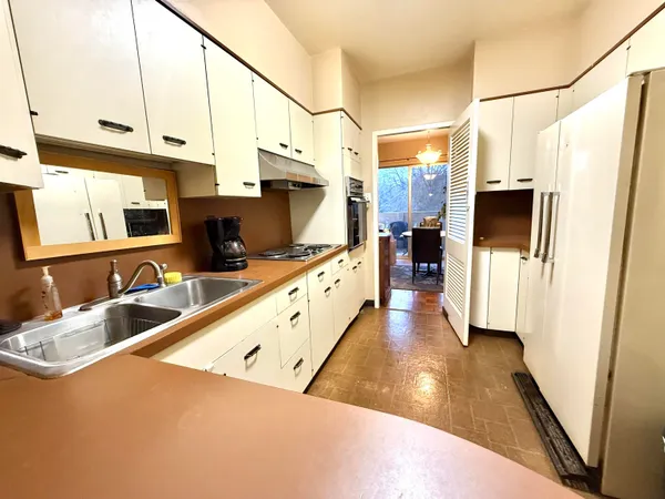a kitchen with stainless steel appliances a refrigerator a sink a stove and white cabinets with wooden floor