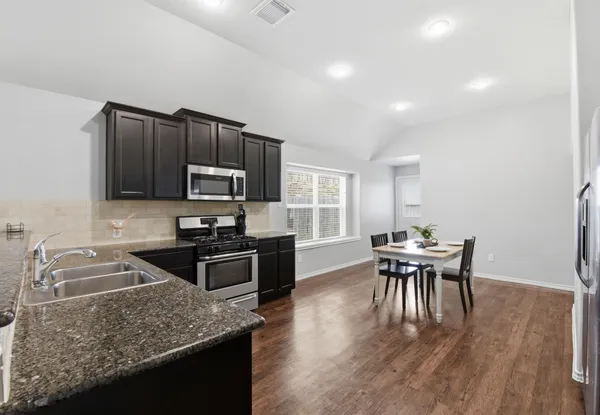 a kitchen with granite countertop kitchen island wooden cabinets and stainless steel appliances