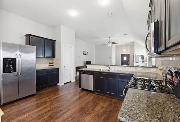 a large kitchen with stainless steel appliances granite countertop a stove a sink dishwasher and a refrigerator