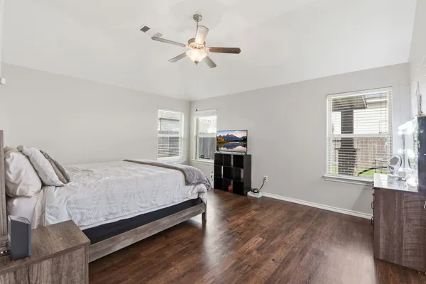 a spacious bedroom with a bed a dresser and wooden floor