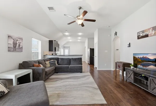 a living room with furniture kitchen view and a wooden floor
