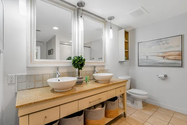 a bath room with a toilet a sink and a mirror