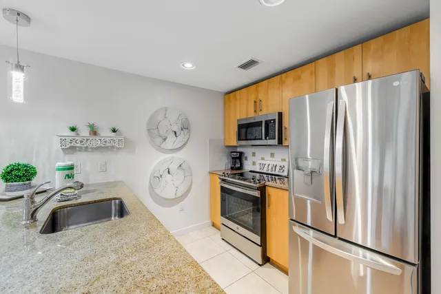a kitchen with stainless steel appliances granite countertop a refrigerator a stove and a sink